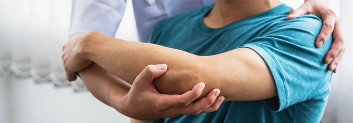 Healthcare professional examining a patient’s elbow for signs of pain.