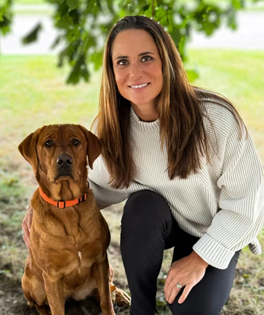 Dr. Sandy Ager providing care to a patient lying on an adjustment table, accompanied by Daphne, her dog, showcasing a relaxed and pet-friendly atmosphere.
