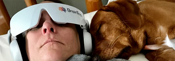 Woman Receiving BrainTap Therapy with a Dog Sleeping On Her Shoulder